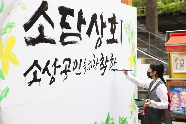 15일 서울 인사동 쌈지길에서 열린 소상공인 플래그십 스토어 개장행사에서 명인의 대형 붓글씨 연출을 통해 코로나19로 지친 소상공인을 위로하고 있다. 사진/중기부