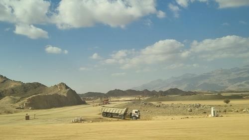 사우디아라비아 북서부 네옴시티로 향하는 도로변을 오가는 덤프트럭. 사진/연합뉴스