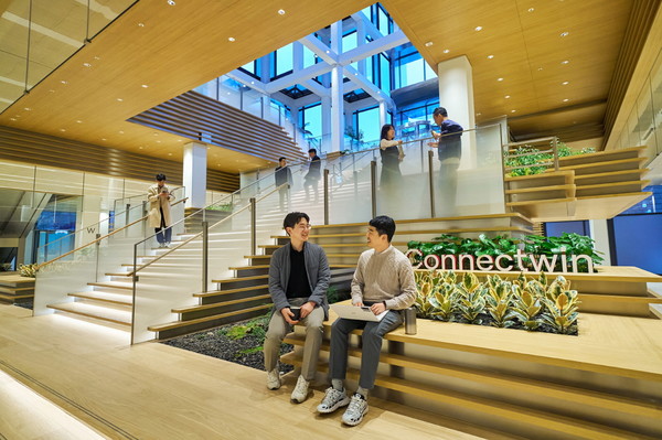 LG 직원들이 LG트윈타워 저층부 공용공간 ‘커넥트윈’에서 대화를 나누고 있다. ‘커넥트윈’의 대형 계단은 1층 로비와 지하 1층을 연결하며, 이동과 휴식의 기능을 결합한 독특한 구조를 갖추고 있다.